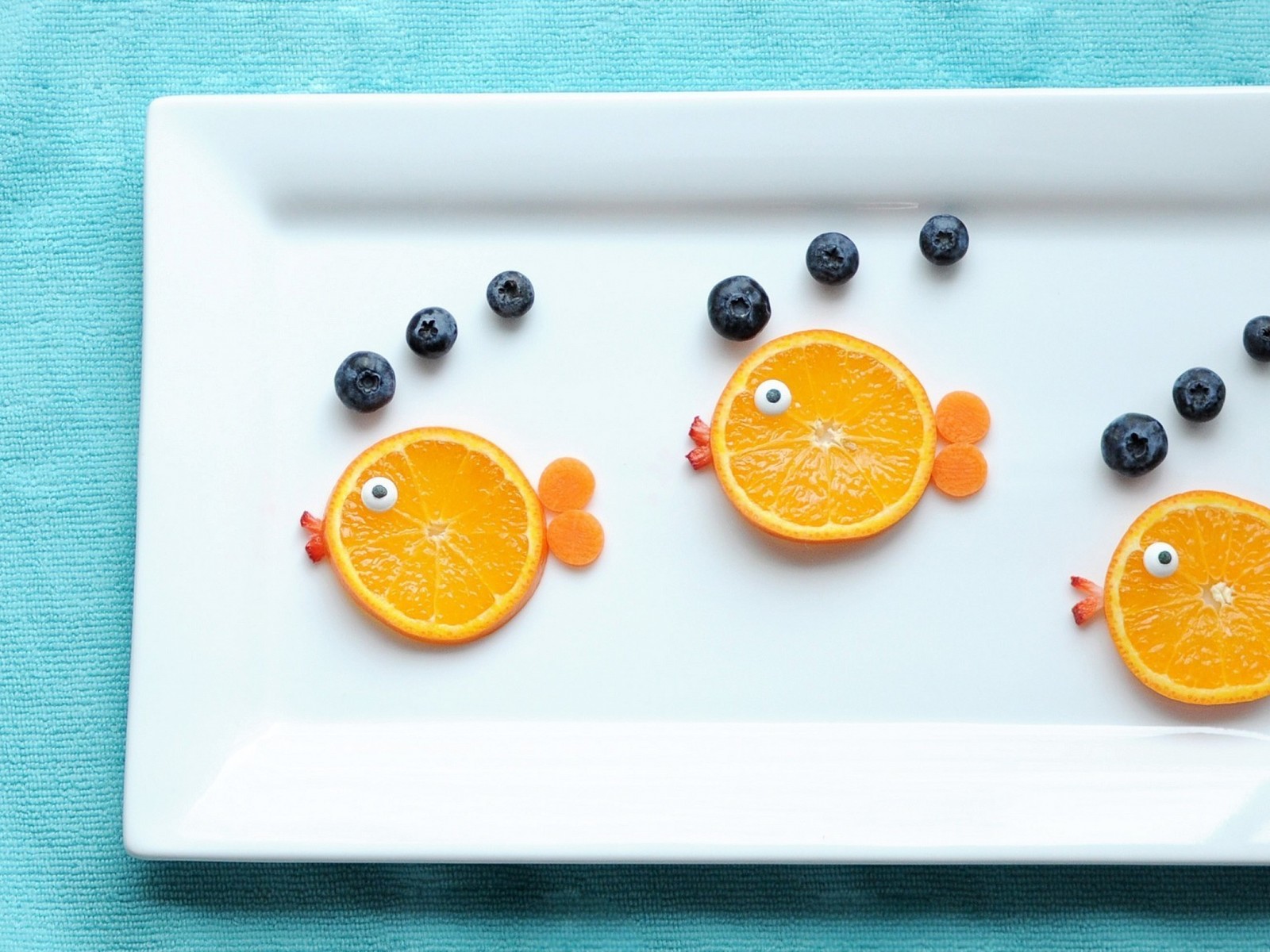 Há fatias de laranja com olhos e mirtilos em um prato (fruta, laranja, comida, waffle, comida saudável)