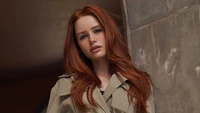 Madelaine Petsch dans une séance photo élégante avec des cheveux rouges flottants et un manteau chic.