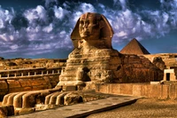 The Great Sphinx of Giza with the Pyramids in the background, showcasing ancient Egyptian architecture under a dramatic sky.