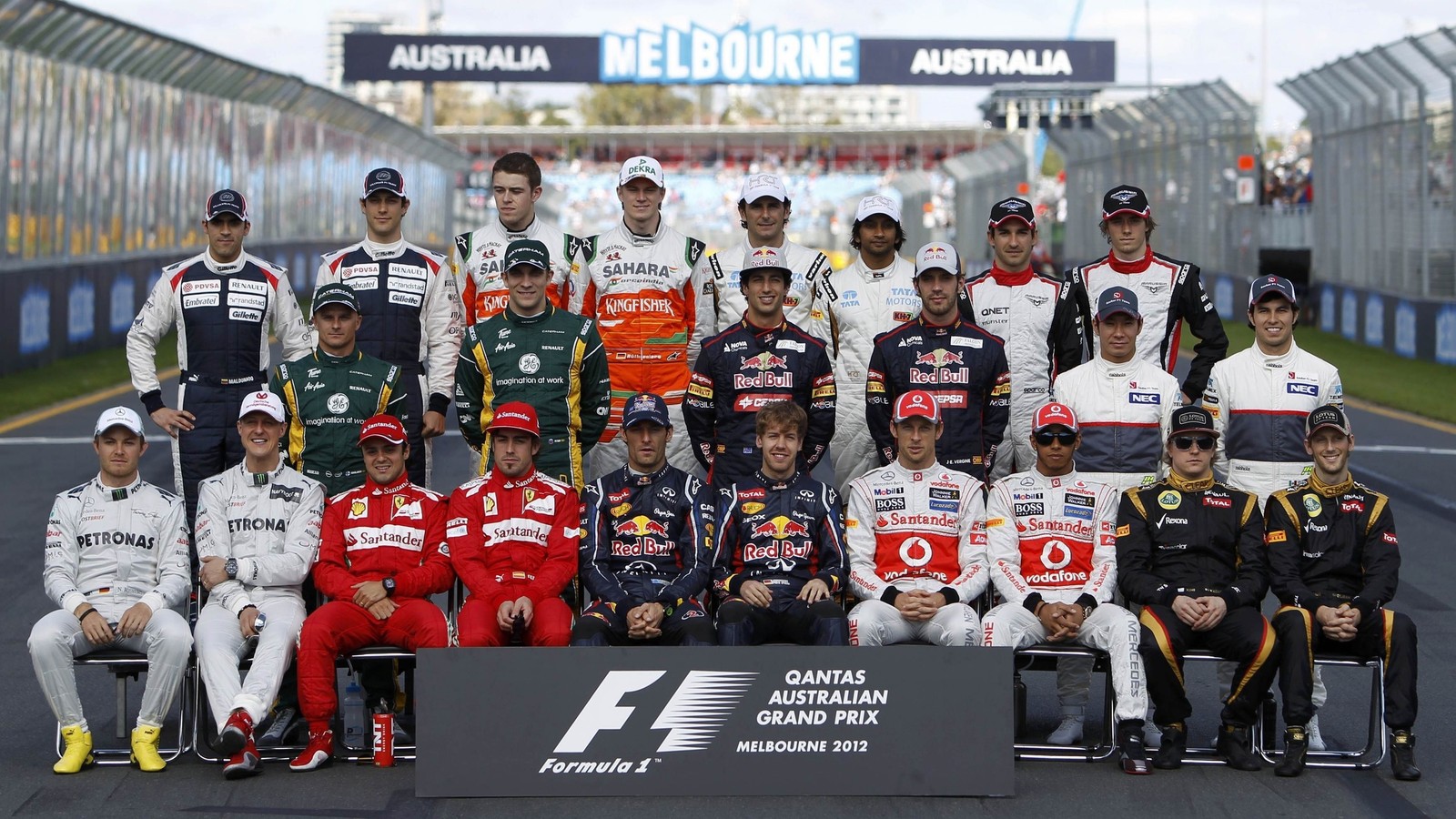 A group of men in racing uniforms posing for a picture (team, sports, racing, car, sport venue)