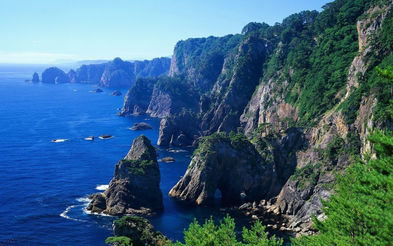 Uma vista de um penhasco rochoso com um corpo d'água (costa, penhasco, klippe, promontório, rocha)