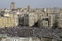 Crowd gathering in a bustling urban square surrounded by towering buildings in a metropolitan city.