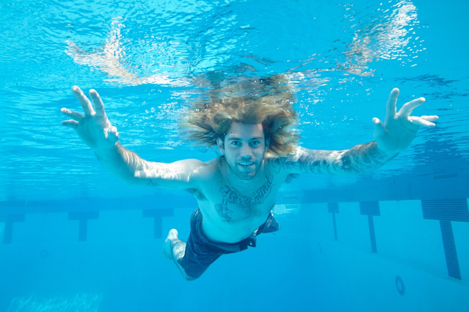 Hay un hombre nadando en una piscina con las manos arriba (nirvana, portada de álbum, álbum, subacuático, diversión)