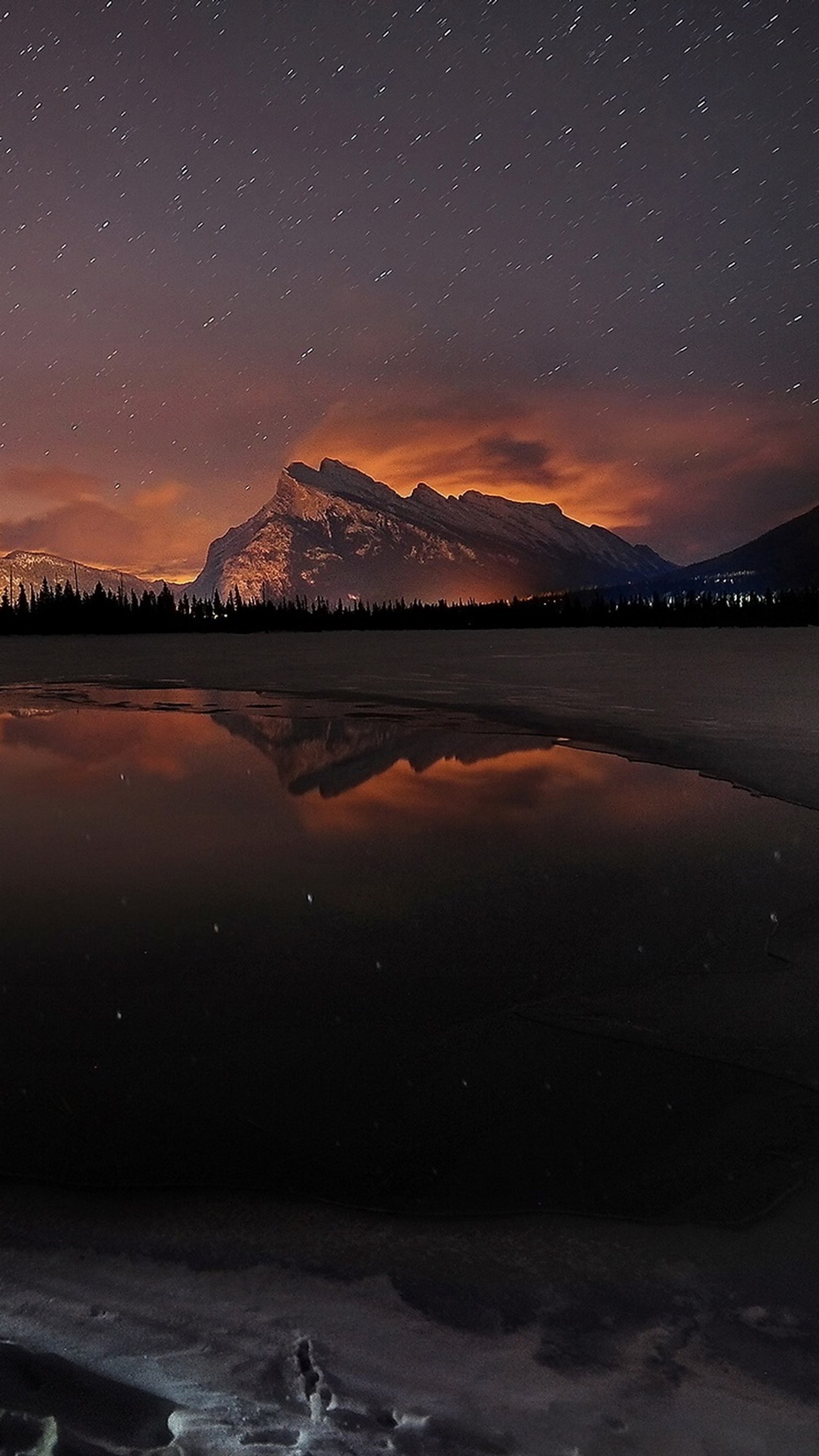 Une montagne au loin avec un lac et un ciel étoilé (ciel)