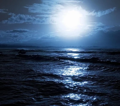 Ondas do oceano iluminadas pela lua sob um céu nublado