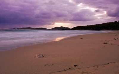 Plage sereine au crépuscule sous des nuages violets