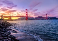 Golden Gate Bridge at sunset, framed by the shimmering waters and a vibrant sky, with Alcatraz Island in the distance.