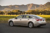 Toyota sedan parked against a scenic backdrop of mountains and fields.