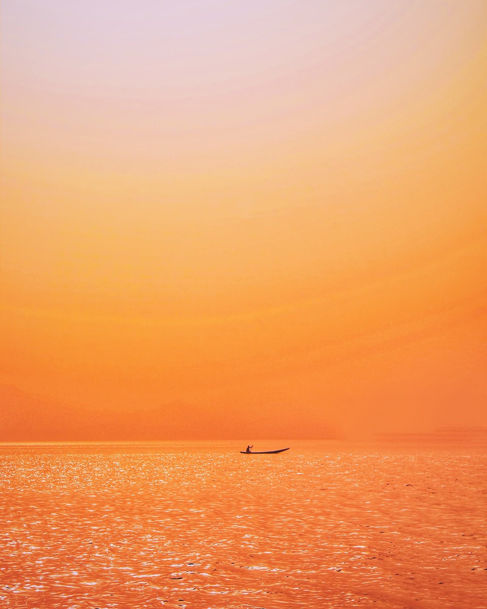 Il y a un bateau flottant dans l'eau au coucher du soleil (horizon, orange, mer, crépuscule, lever de soleil)