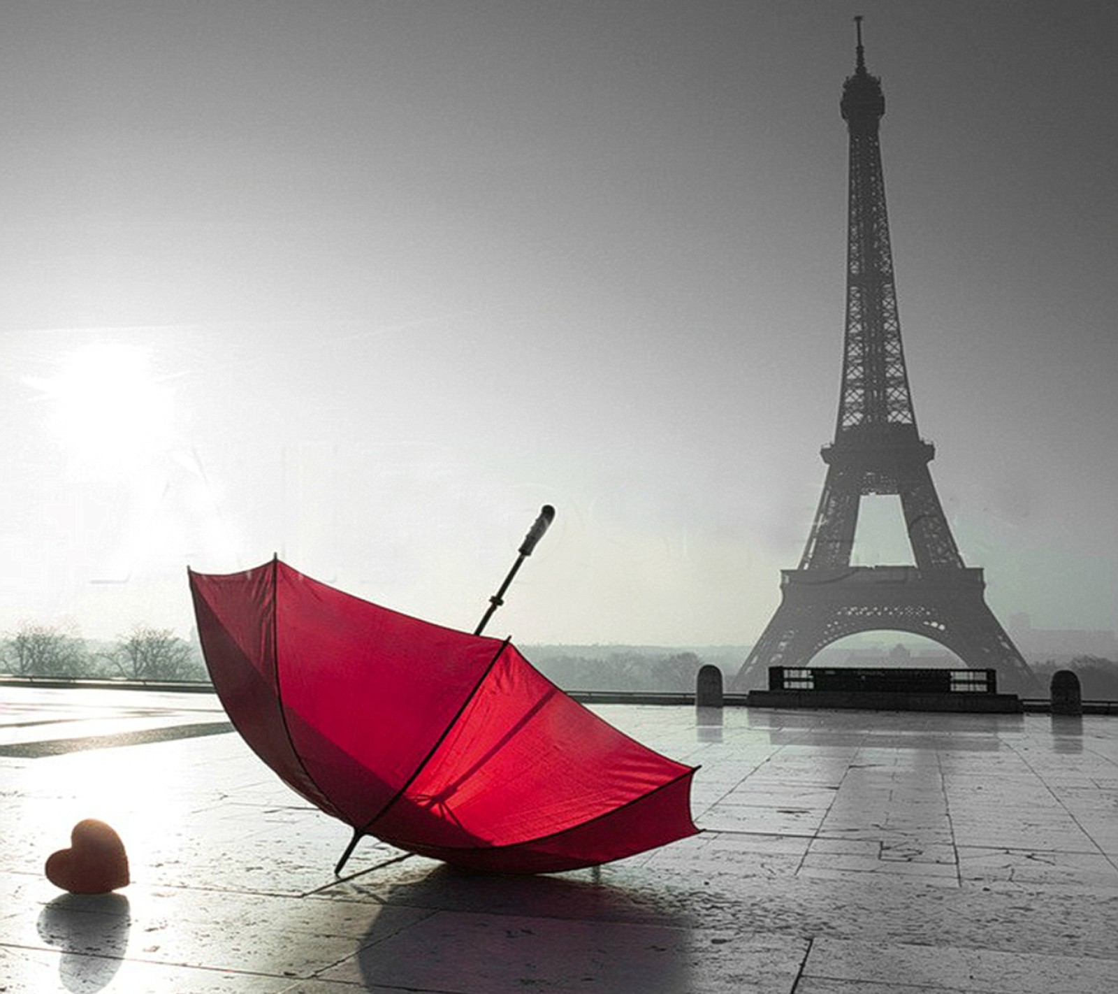 Há um guarda-chuva vermelho sentado no chão ao lado de uma bola (cidade do amor, paris)