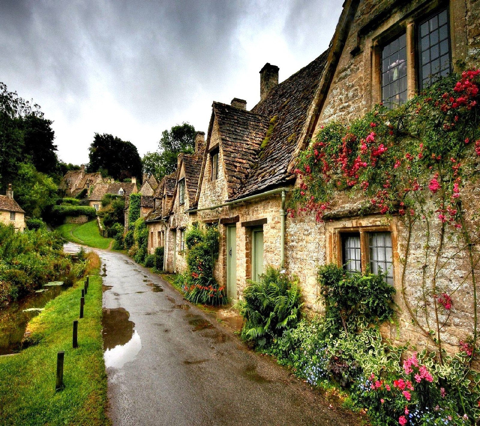 Arafed stone houses with flowers and a stream in the middle of a road (nature)