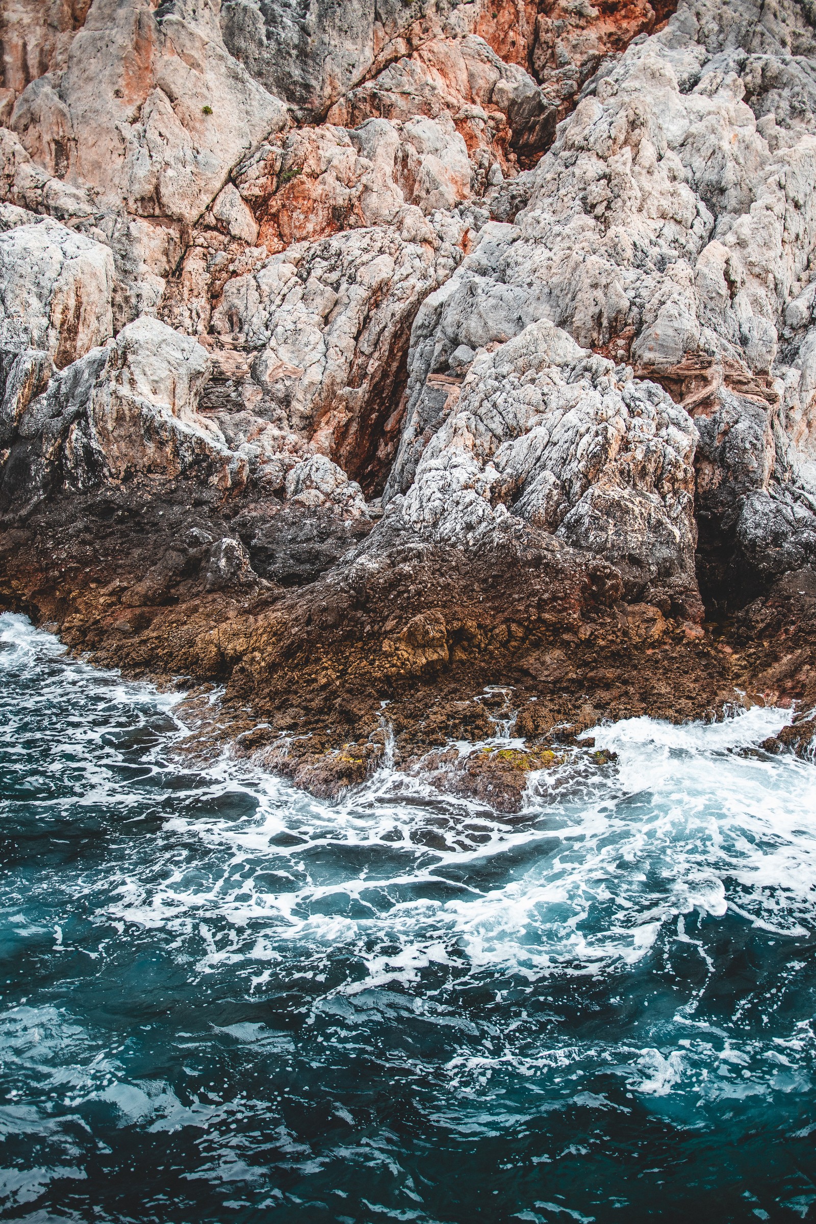 Hay un hombre de pie en una tabla de surf en el agua (geología, ola, costa, agua, roca)