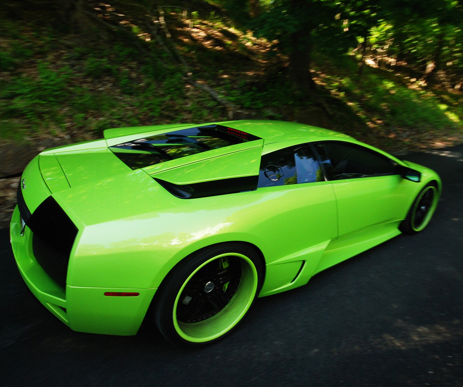 A close up of a green sports car driving down a road (best, car, lamborghini)