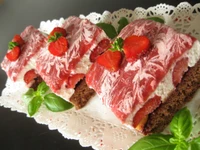 Delicious strawberry cake layered with whipped cream and fresh strawberries, garnished with basil.