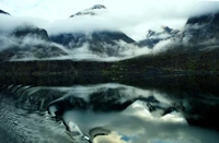 Reflexión tranquila de montañas y nubes en un lago glacial