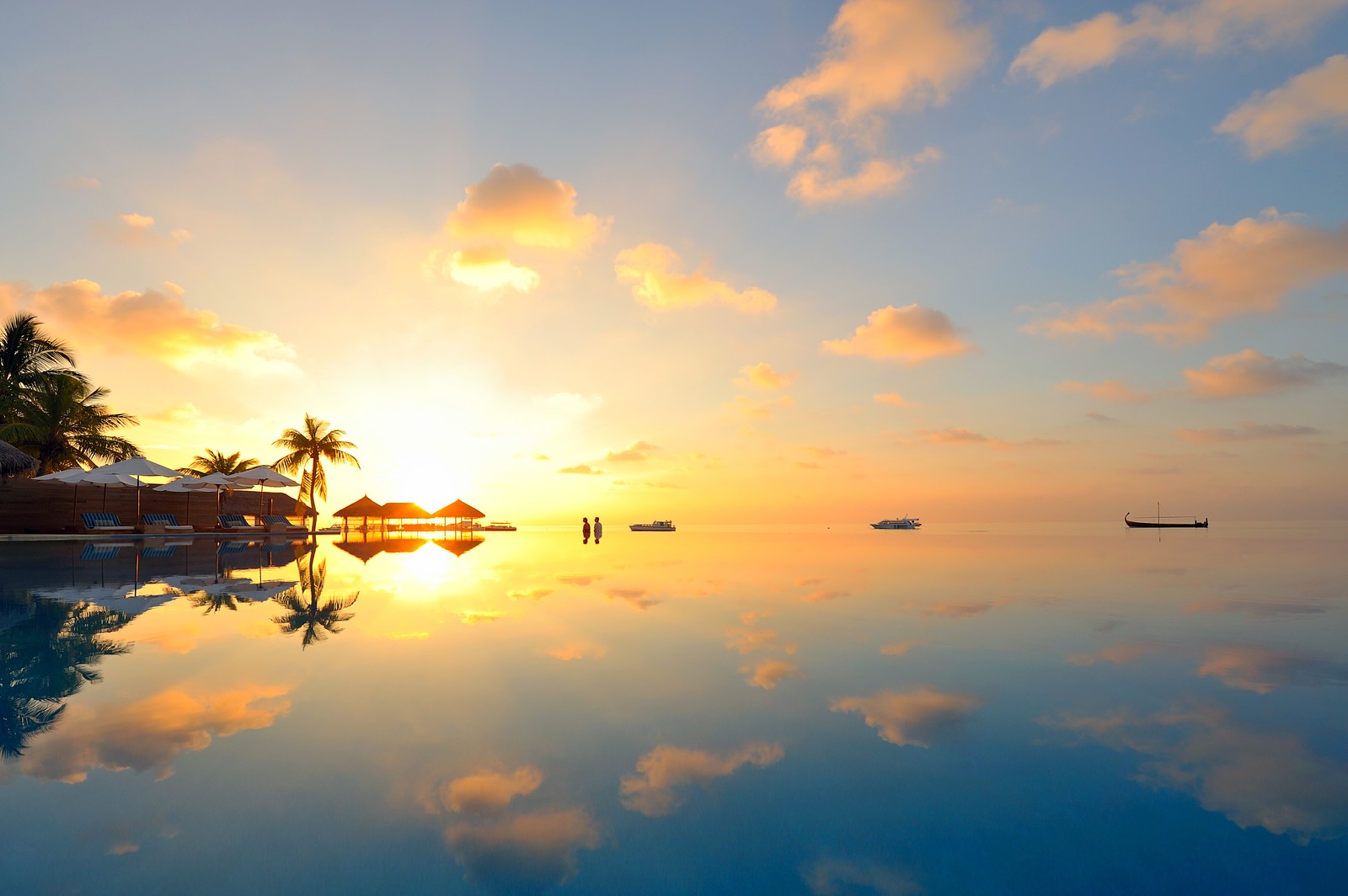 Sunset over a pool with palm trees and a boat in the distance (sunset, island, water, reflection, sunrise)