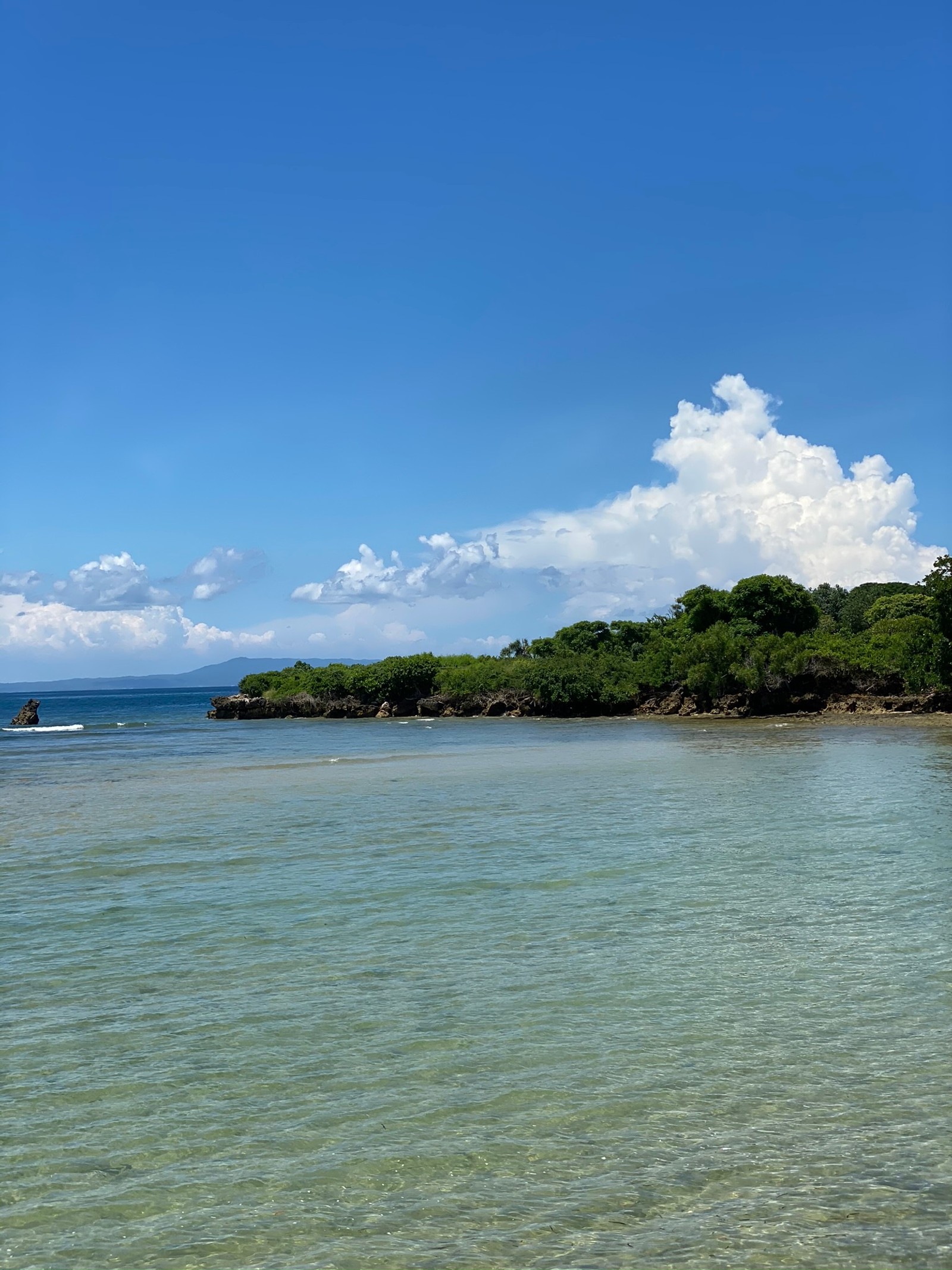 Hay un bote en el agua cerca de una playa (mar, cuerpo de agua, nube, recursos hídricos, vía fluvial)