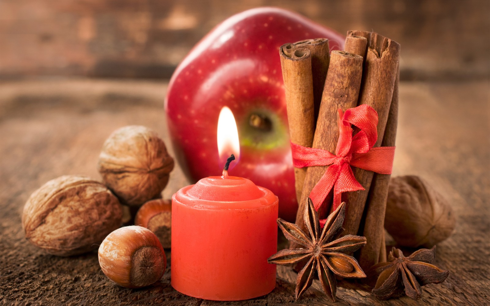 Hay una vela y algunos nueces y una manzana sobre una mesa (manzana, naturaleza muerta, alimentos naturales, comida, superalimento)