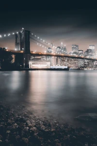 Pont de Brooklyn la nuit : lumières de la ville et reflets sur le fleuve Hudson