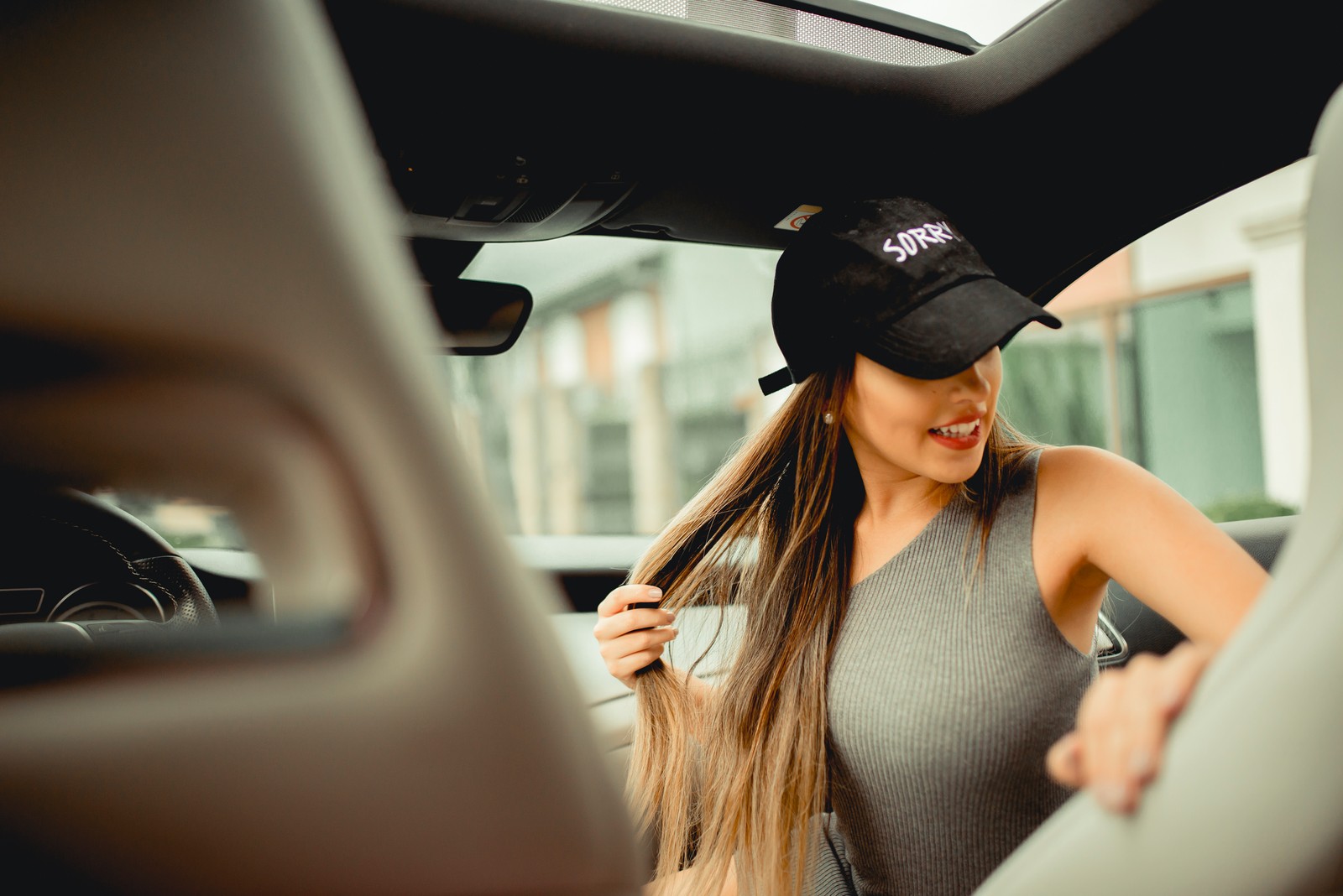 Une femme arafed dans une voiture avec une casquette de baseball (cheveux, vidéo, musique, cheveux longs, beauté)