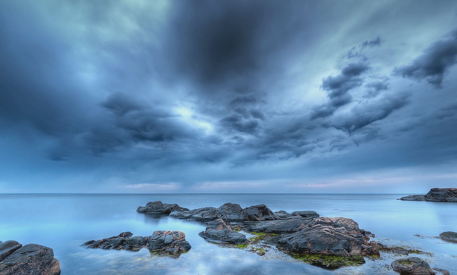 Une vue d'un ciel nuageux au-dessus d'un plan d'eau (mer, nuage, eau, océan, rivage)