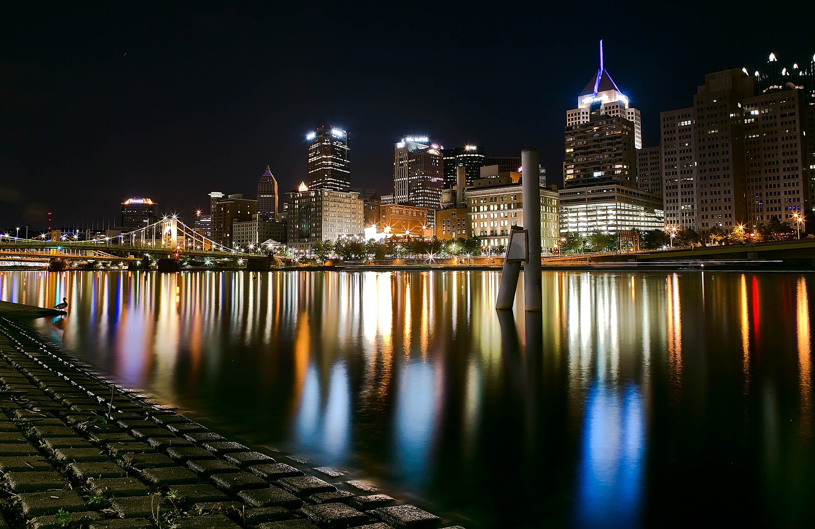 Une vue archaïque d'une ville la nuit avec un pont et une rivière (paysage urbain, ville, nuit, horizon, métropole)