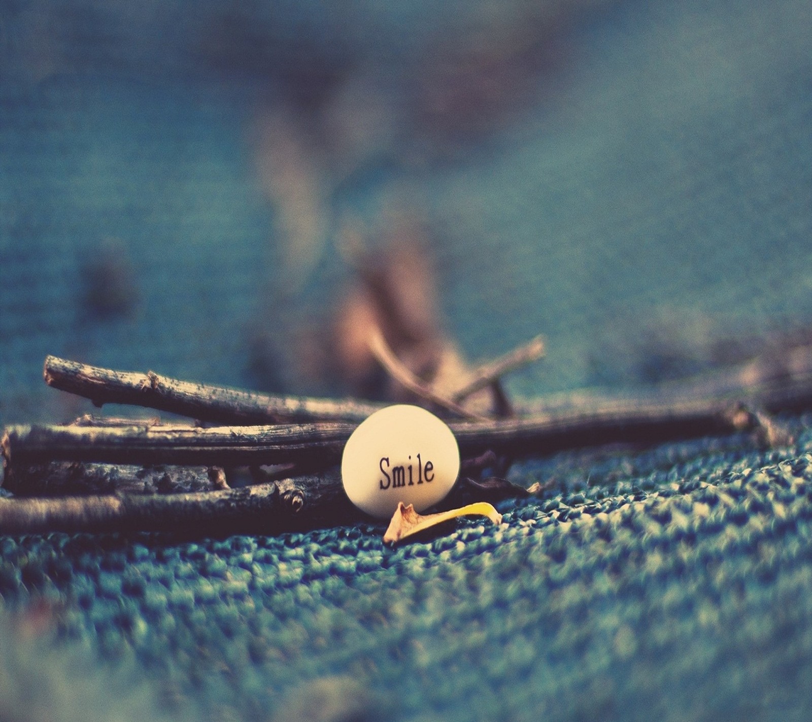 There is a small white stone sitting on a blue cloth (metal, smile)