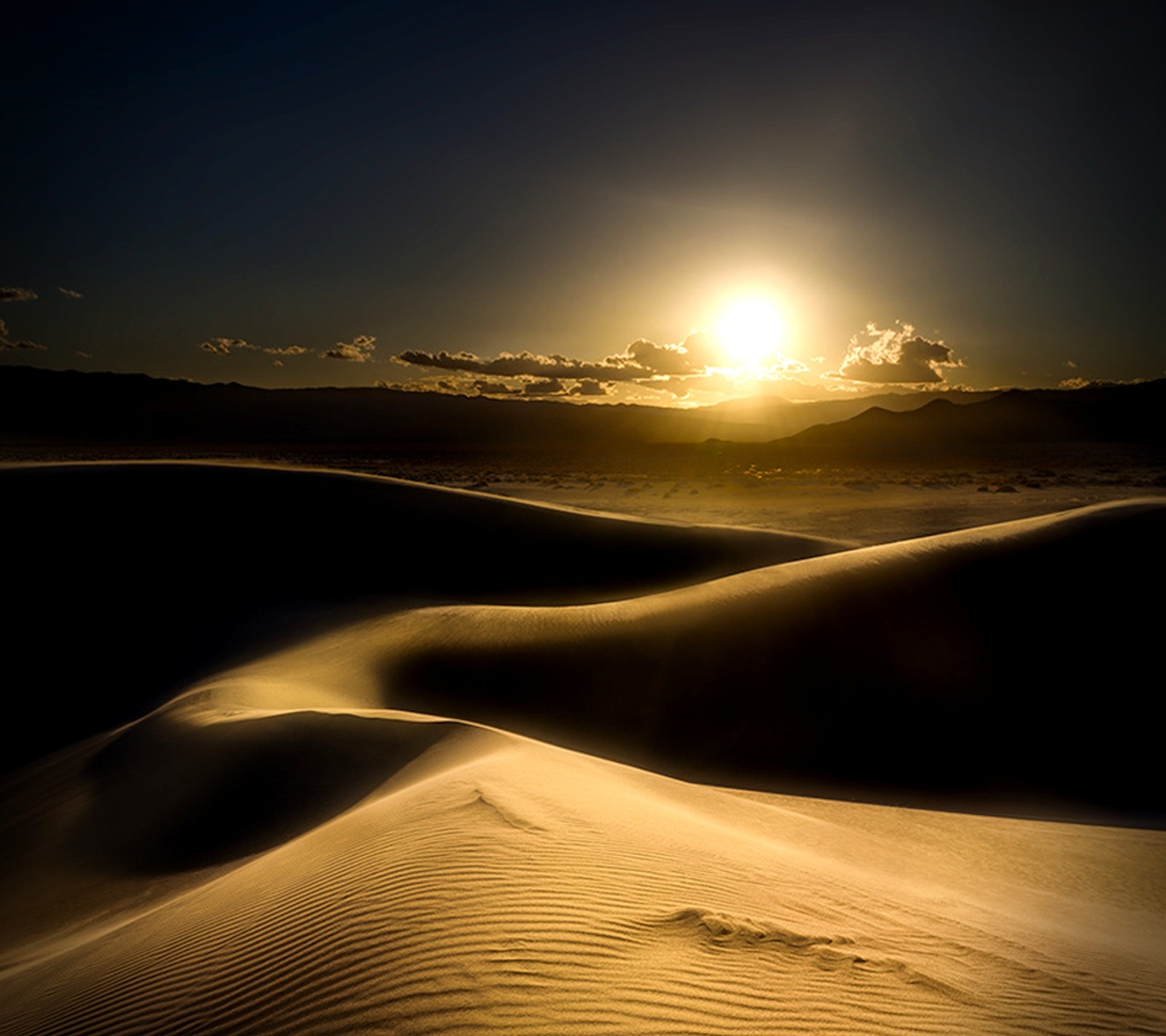 Arafed view of a desert with a sun setting in the background (golden, sunset)