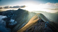 Cresta montañosa iluminada por el sol bajo un cielo dramático