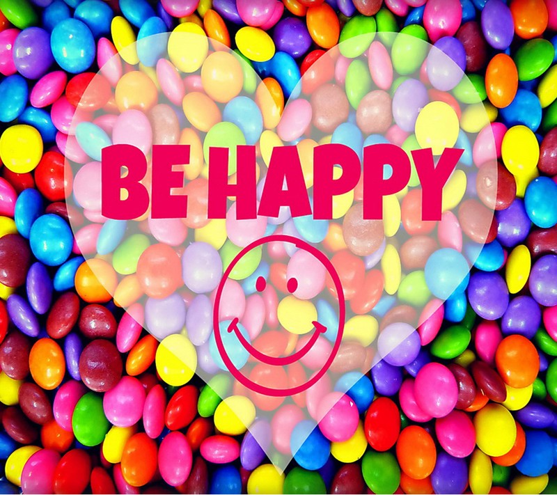 A close up of a heart shaped sign surrounded by colorful candies (be, happy)