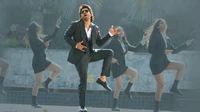 Allu Arjun dans une performance de danse stylée entouré de danseurs en tenue formelle