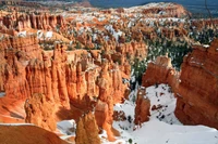 Schneebedeckte Hoodoos erheben sich majestätisch in der lebhaften orangefarbenen Landschaft des Bryce Canyon Nationalparks und zeigen beeindruckende geologische Formationen in einer Winterlandschaft.