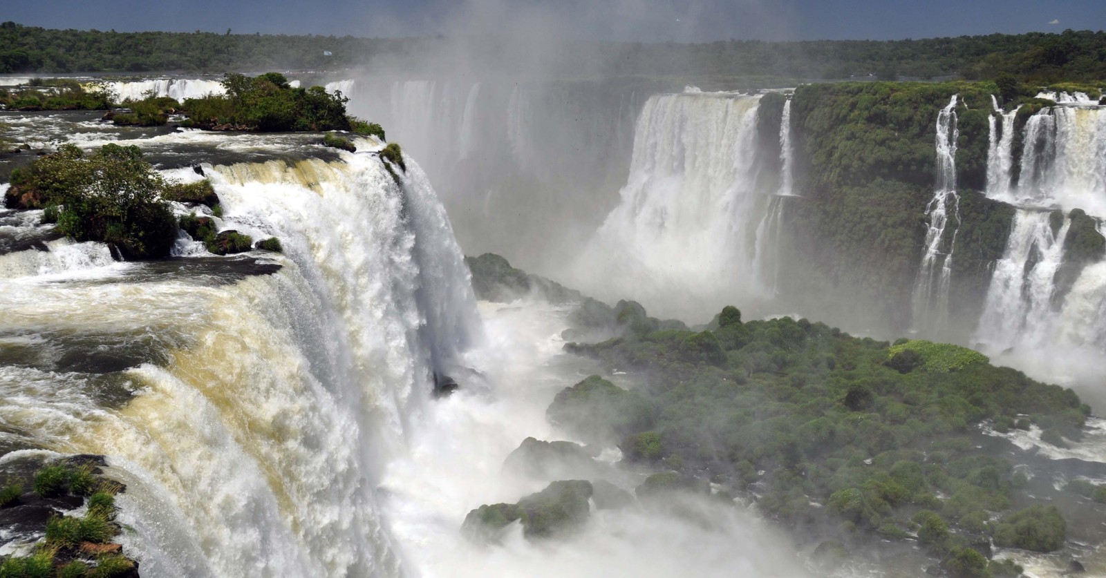 Vista de una cascada con unos árboles en primer plano (cataratas del iguazú, río iguazú, cascada, recursos hídricos, cuerpo de agua)