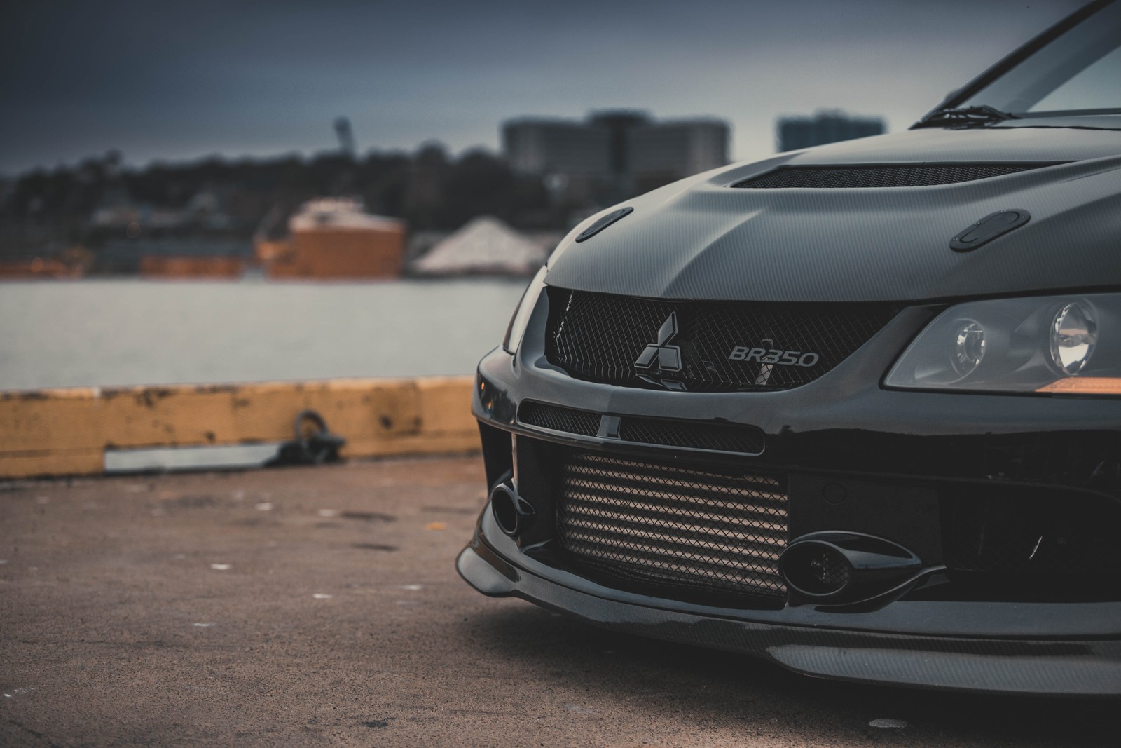 Un primer plano de un coche negro estacionado en una calle (mitsubishi lancer evolution, coche, parachoques, mitsubishi, exterior de automóvil)