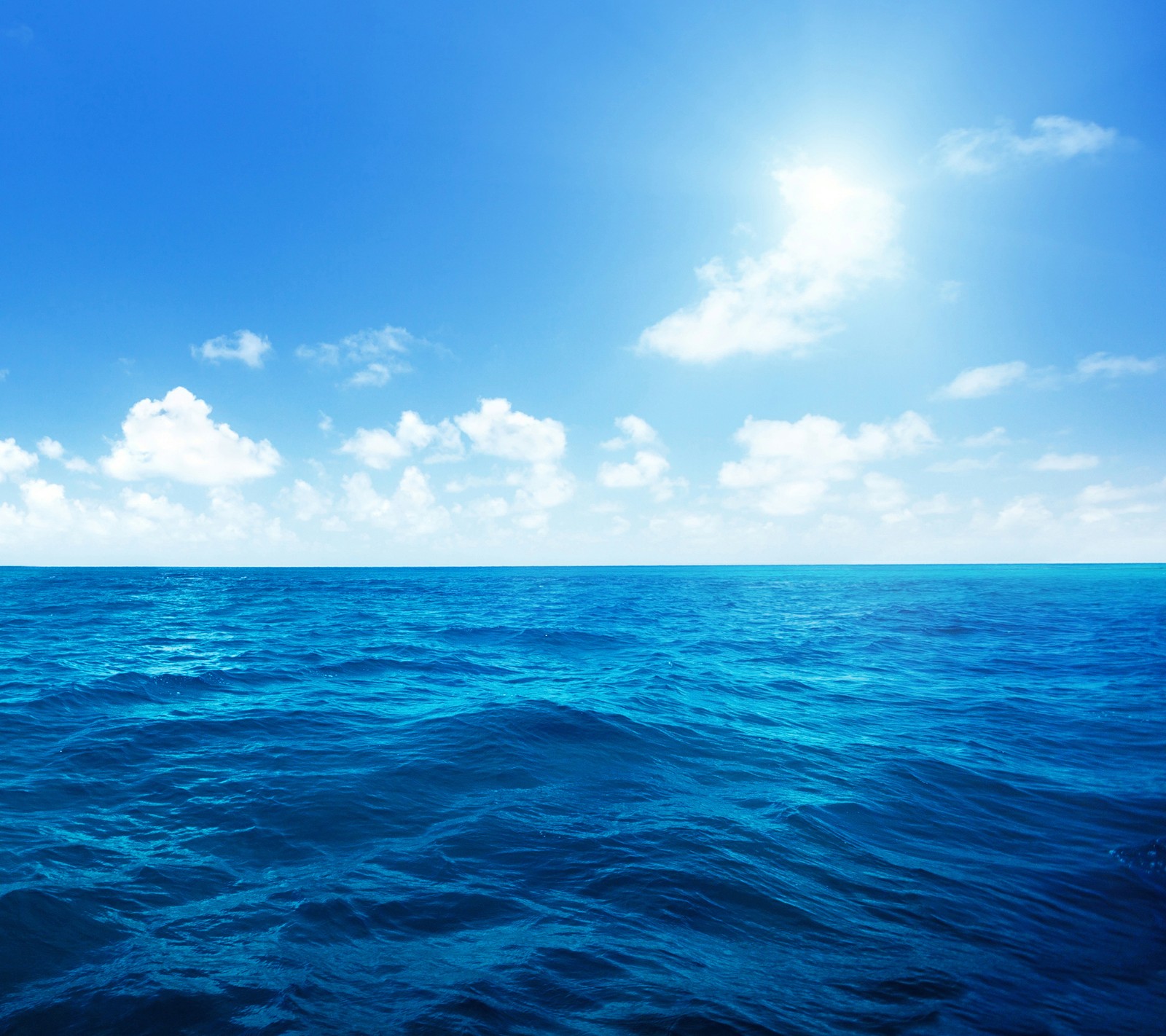 A view of the ocean with a bright sun shining over it (blue, horizon, ocean, sea, sky)