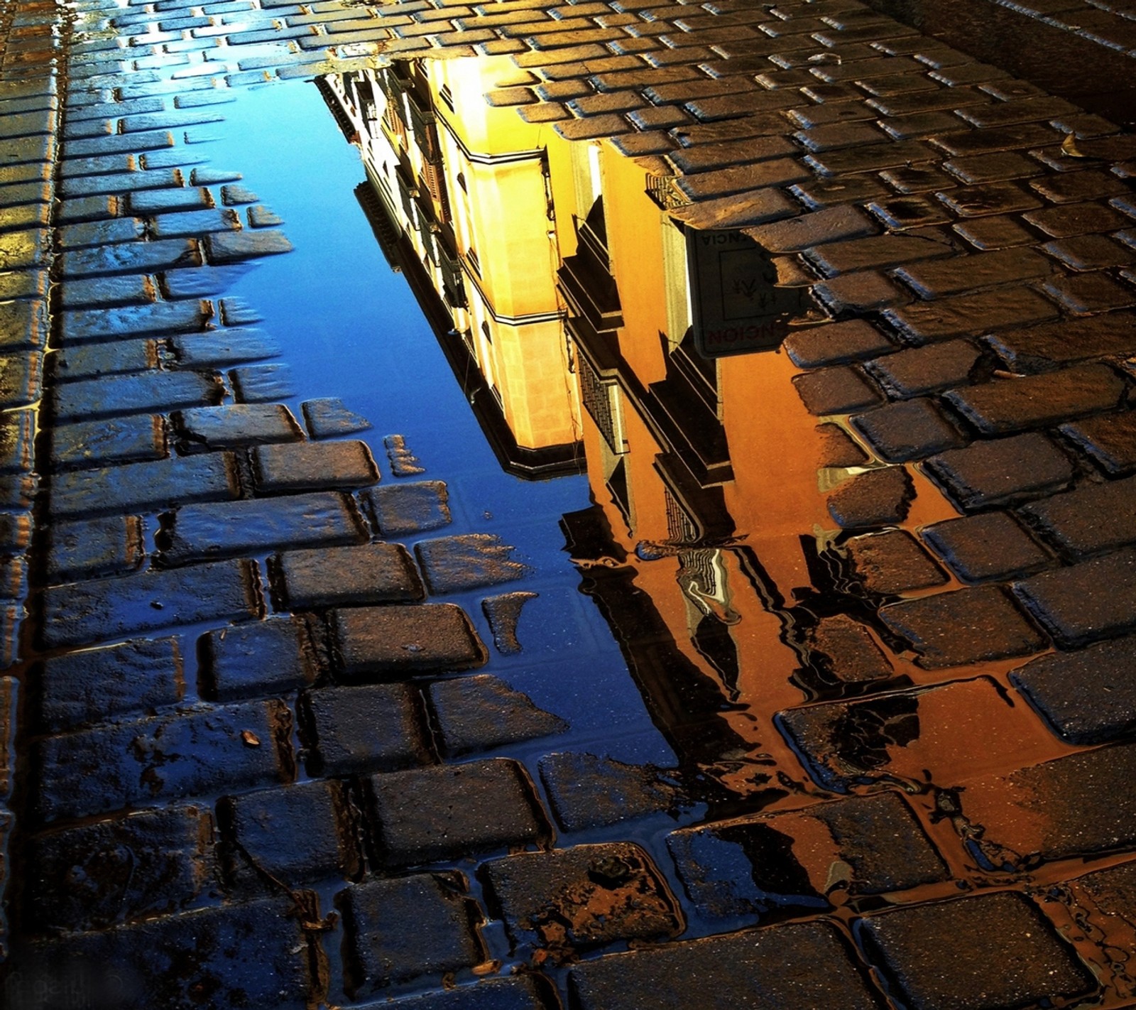 Une image graphique d'un bâtiment reflété dans une flaque d'eau (avenue, brique, bâtiment, flaque, réflexion)