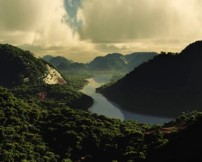 Serene River Valley Amidst Lush Hills and Dramatic Clouds