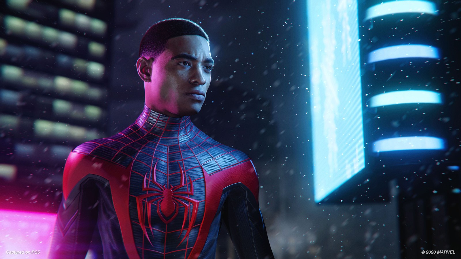 Spider-man en costume se tenant dans la neige devant une ville néon (miles morales, marvels spider man miles morales, playstation 5, jeux 2020, 2020 games)