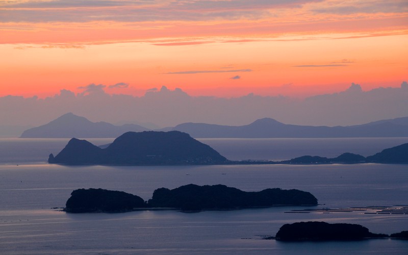 Вид на закат над водоемом с горами вдали (99 islands, острова куджуку, nagasaki prefecture, sasebo, япония)