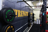 Zona de entrenamiento de fuerza con barra y discos de peso