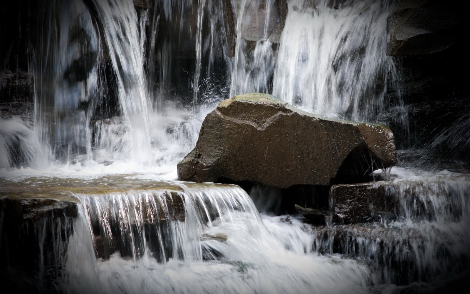 Hay una gran roca en medio de una cascada (cascada, cuerpo de agua, recursos hídricos, agua, naturaleza)