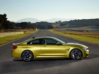 Sleek BMW M4 Coupé in vibrant yellow, poised on an open road with a scenic backdrop.