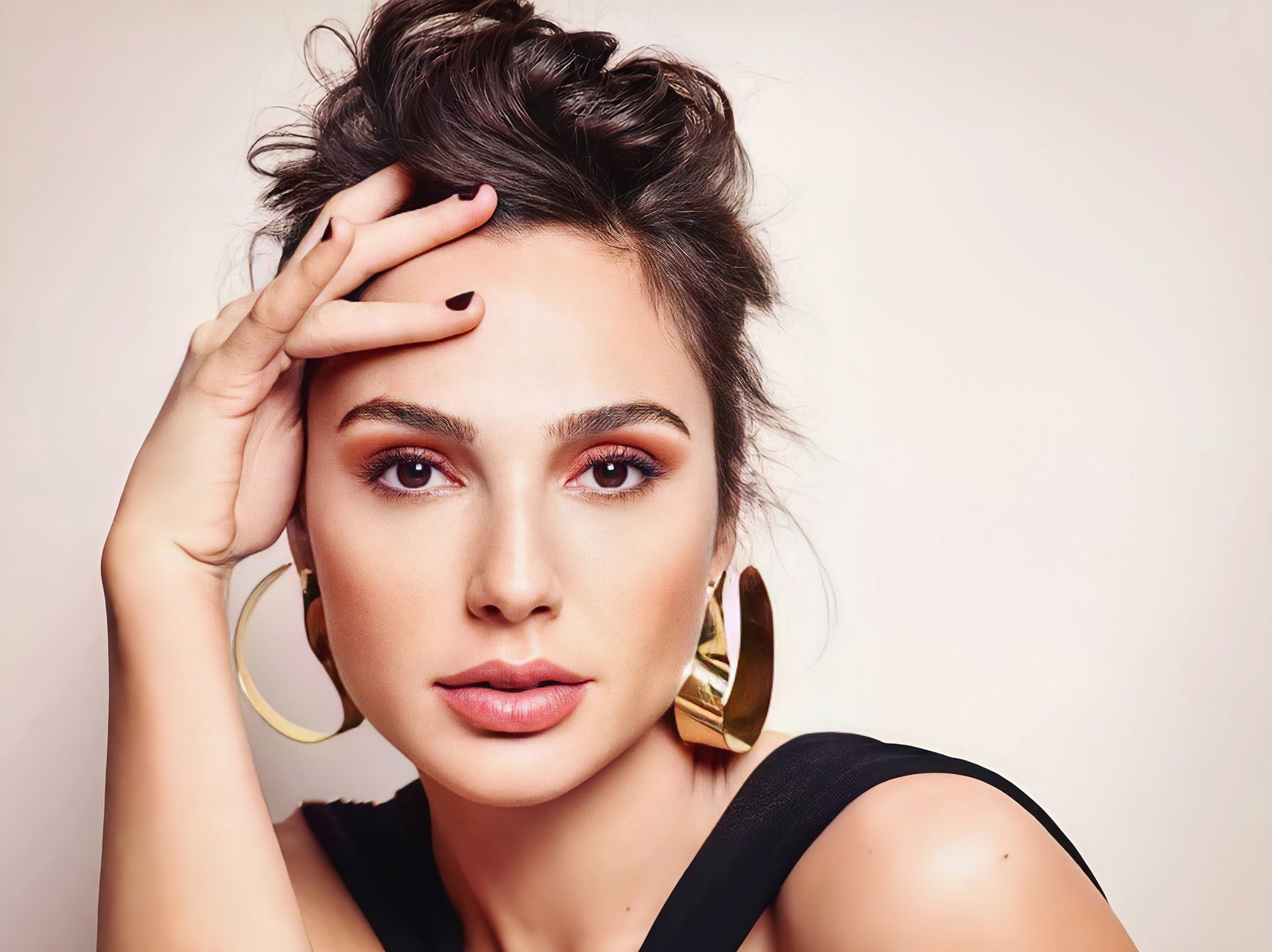 Un gros plan d'une femme en robe noire et boucles d'oreilles dorées (gal gadot, portrait, visage, gros plan, 2020)