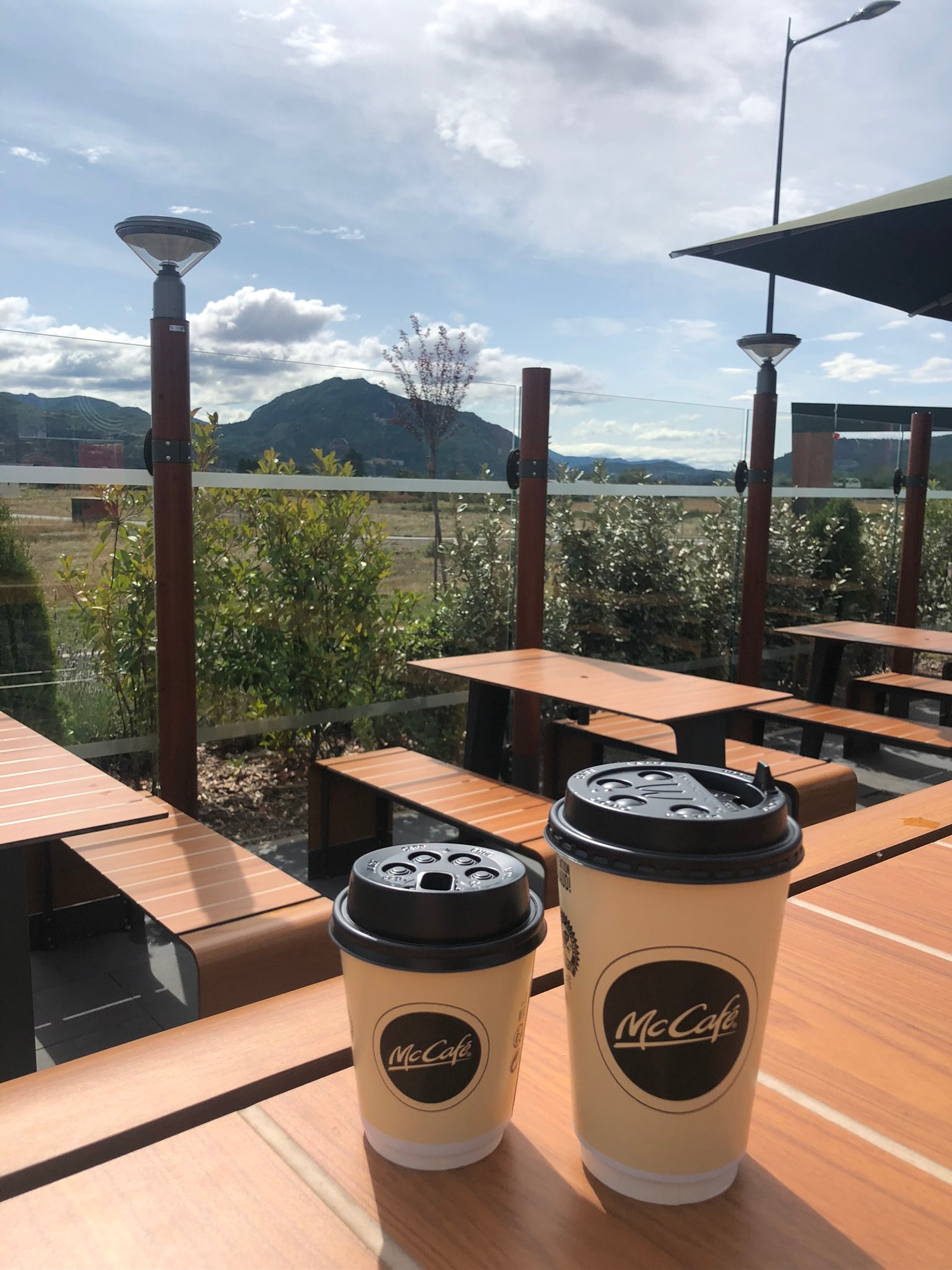 Zwei kaffeetassen stehen auf einem tisch in einem restaurant mit aussicht (außenstruktur, holz, hartholz, holzbeize, schatten)