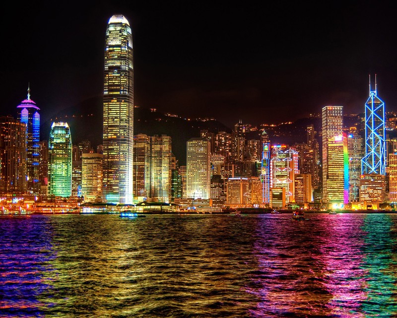 O horizonte de hong kong à noite com luzes coloridas refletindo na água (bonito, edifícios, cidade, lago, arco íris)