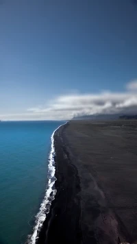 Serener Kontrast von türkisfarbenem Wasser und schwarzem Sand