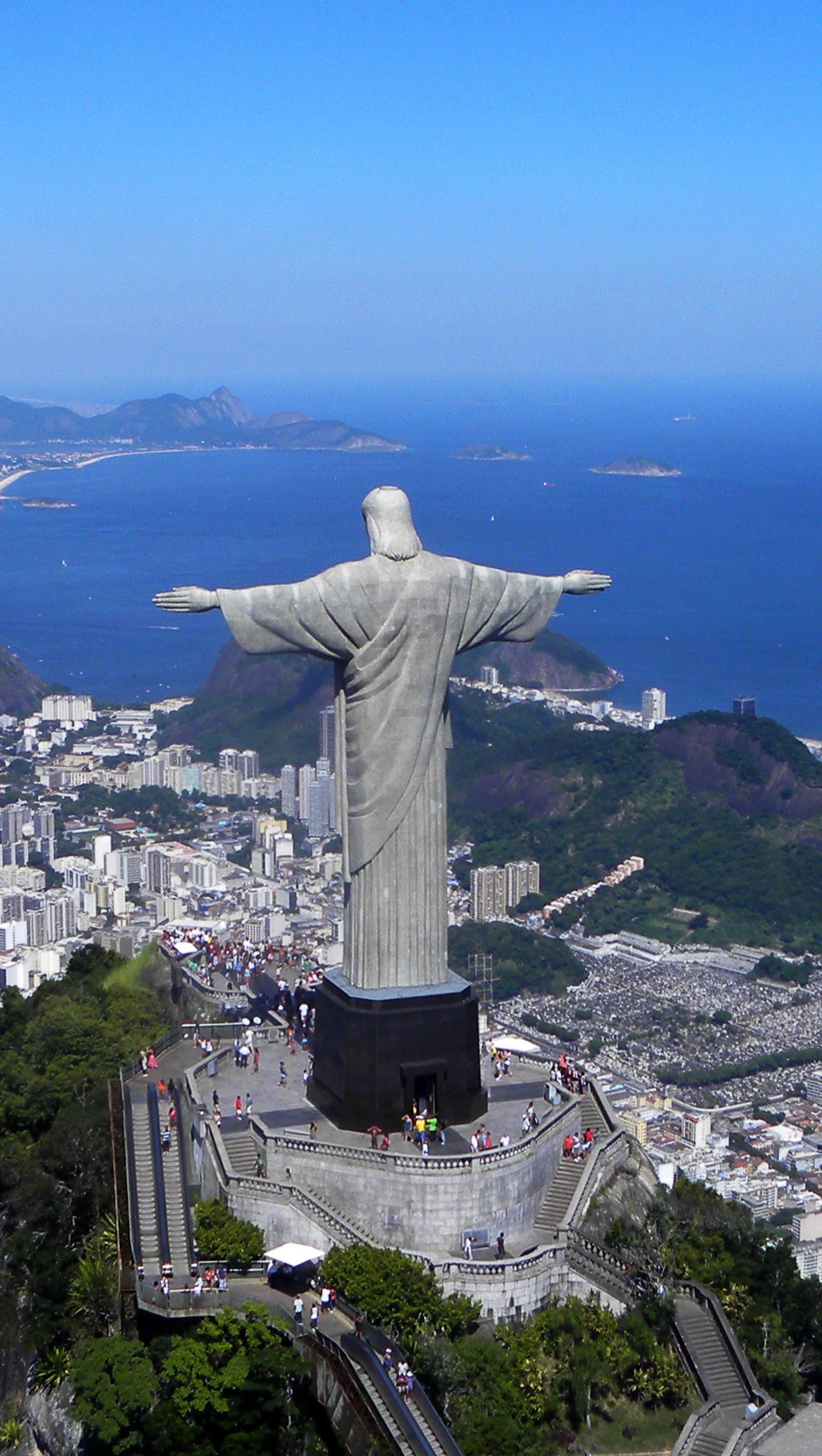 Arafed statue of christ overlooking a city and the ocean (b54, m76)