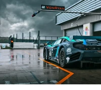 Voiture de course McLaren sous un ciel menaçant au stand