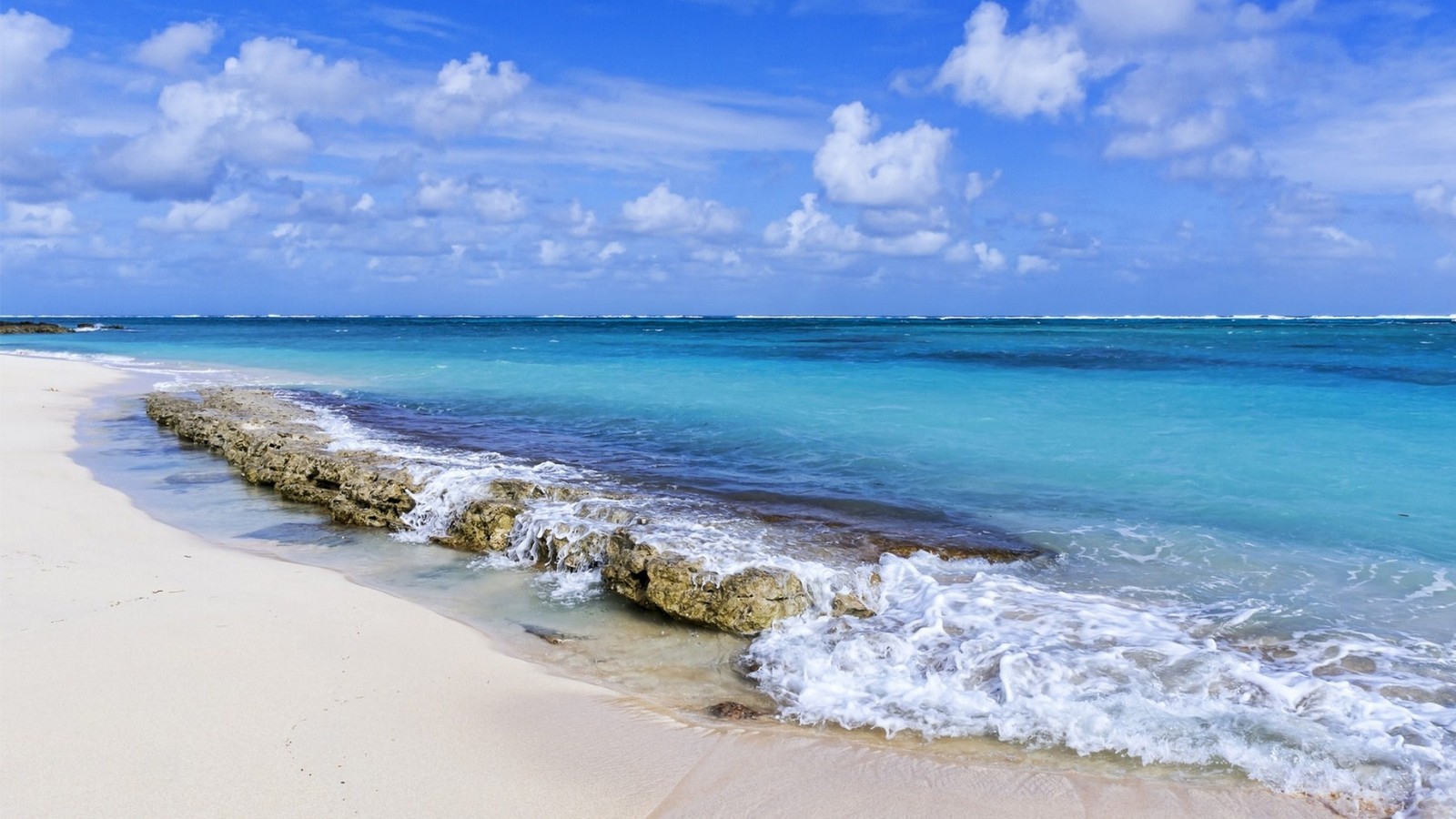 Une vue d'une plage avec une côte rocheuse et une eau claire (plage, mer, rivage, océan, la côte)