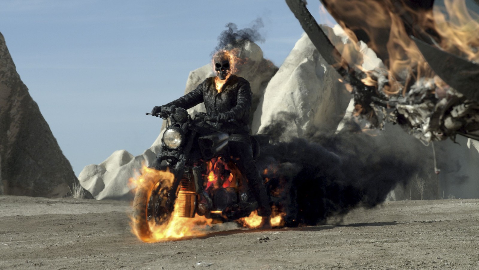 Un hombre montando una motocicleta en una carretera desértica con fuego en el aire (especialista, columbia pictures, película)